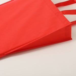 A red non-woven tote bag with handles, featuring a structured design and a branding logo.