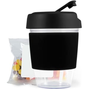 A reusable coffee cup with a black silicone sleeve and a secure lid, accompanied by a pack of colorful jelly beans.