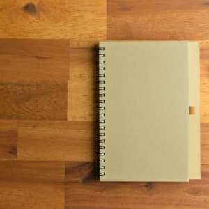 A beige spiral-bound notebook on a wooden surface.