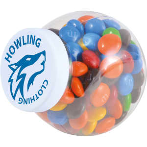 A clear container filled with M&M's in various colours, including blue, green, red, yellow, and black, featuring a logo on the lid.