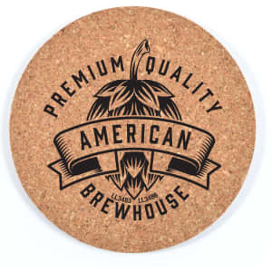 A round cork coaster featuring a black design with a hop illustration and text detailing quality and brewhouse.