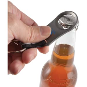 A drink bottle opener in gray is being used to remove a cap from a glass bottle of beverage.