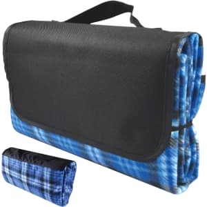 A folded blue and black picnic blanket with a carrying handle, featuring a plaid design. Includes a logo.