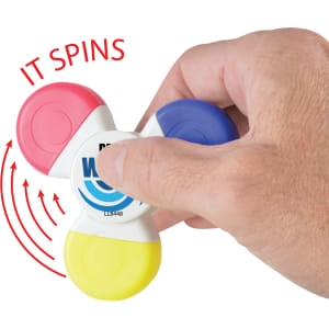 A Spinner Highlighter with red, blue, yellow, and pink sections, held in a hand, featuring the text "IT SPINS".