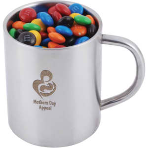 A stainless steel mug filled with red, yellow, blue, green, brown, and orange M&M's, featuring a logo.