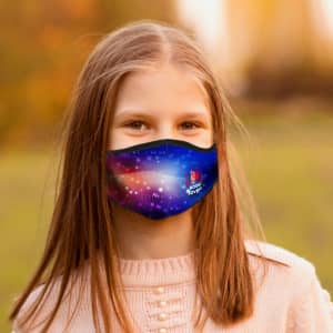 A blue children's face mask features a vibrant, colourful design, displayed on a young girl in an outdoor setting.