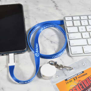A blue lanyard cable connected to a phone, with a white clip and a keychain, placed next to a keyboard.