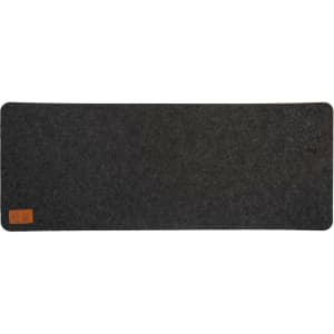 A dark gray desk mat with a felt texture and a small leather label in one corner.