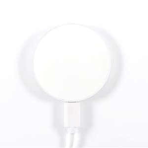 A circular, magnetic wireless charger with a white surface and a white cable attached.