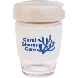 A reusable coffee cup in clear with a white silicone band and a natural-colored lid, featuring a logo.
