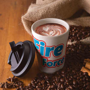 A reusable coffee cup in cream with a black comfort lid, surrounded by coffee beans and cinnamon.