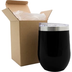 A reusable black coffee cup with a clear lid beside a brown cardboard box. The cup features a metallic base and has a logo.