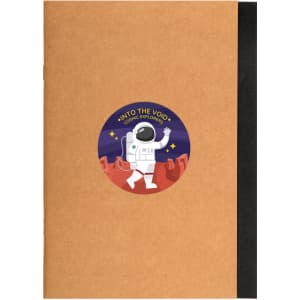 A brown A5 notebook with a black spine and a colorful astronaut sticker on the front.