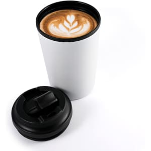 A white reusable coffee cup with a black lid, featuring a latte with a heart-shaped design.