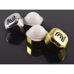 Two lip balm containers, one clear and one gold, featuring rounded white balm. Each has a logo on the lid.