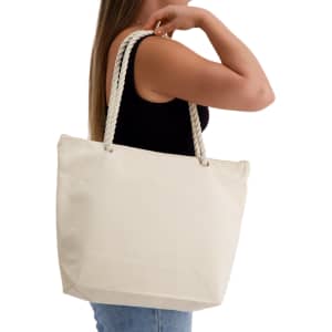 A cream-coloured tote bag with rope handles, held by a woman wearing a black top.