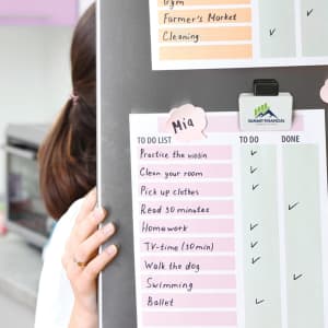 A magnetic clip in white and black, holding a colorful to-do list on a board, featuring a logo.