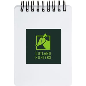 A spiral-bound pocket notebook with a white cover featuring the logo of "Outland Hunters" in green and black.