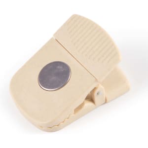 A beige magnetic clip with a textured grip and silver circular accent, featuring a logo.