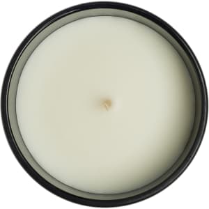 A medium Gleam Glass Candle featuring a smooth, white wax surface with a centered wick, contained in a sleek black jar.