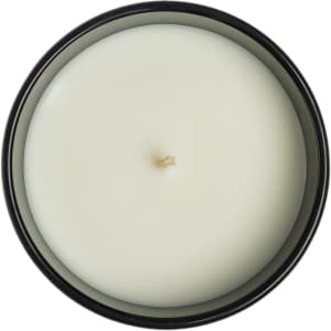 A large glass candle in a black container, featuring a smooth, white wax surface and a centered wick.