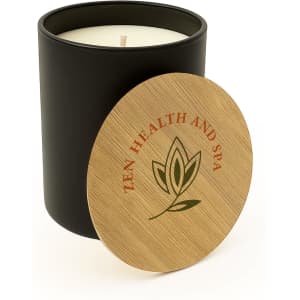 A large black glass candle with a wooden lid featuring a logo. The candle is cream-coloured inside.