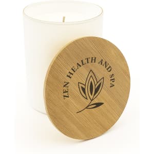 A large white glass candle with a wooden lid featuring a logo and a simple leaf design.