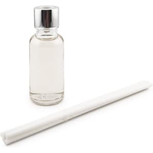 A clear glass bottle with a silver cap and a white reed stick beside it.