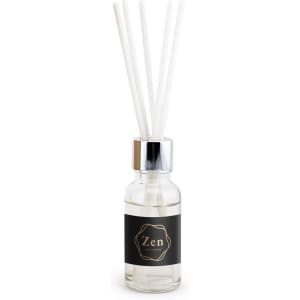 A vanilla reed diffuser in a transparent glass bottle with a black label and four white reeds.