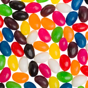 A mix of assorted mini jelly beans in vibrant colours including pink, yellow, green, blue, and black, featuring a glossy finish.