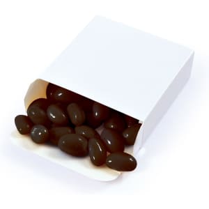 A box of black jelly beans is partially opened, with several beans spilling out onto a white background.