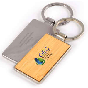 A rectangular bamboo keytag with a silver metal keyring, featuring a logo on the bamboo surface.