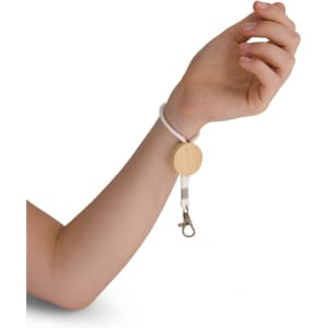 A wrist keytag featuring a wooden circular base and a white elastic cord with a silver clip attachment.