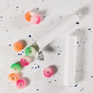 Assorted fruit-flavored gummy rings in various colors, scattered around a partially opened roll.