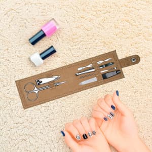 A cork manicure set with scissors, files, and nail polishes in pink and white, displayed on a soft surface.