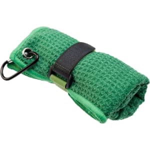 A green travel towel, rolled up with a black strap and carabiner for attachment. It has a textured surface.
