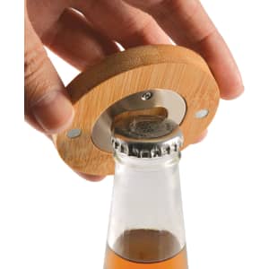 A drink bottle opener made of bamboo, featuring a metallic bottle cap remover, being used on a glass bottle.