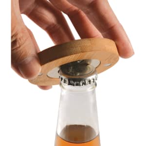 A drink bottle opener made of bamboo is being used to remove a bottle cap, with a clear glass bottle underneath.