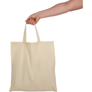 A hand holds a natural-coloured tote bag with short handles, featuring a plain design and no visible branding.
