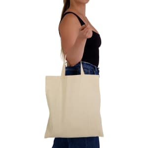 A model holds a beige calico tote bag with short handles, featuring a simple design.