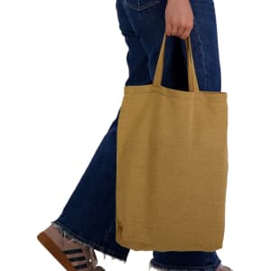 A person holding a mustard yellow reusable tote bag with short handles, dressed in denim.
