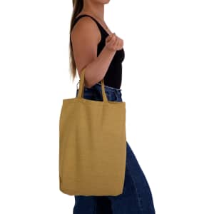 A person holds a mustard yellow tote bag with short handles, featuring a simple design.