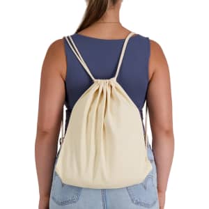A cream-coloured drawstring backpack is worn on the back of a person, showcasing its simple design and straps.