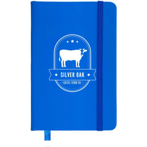 A blue notebook with a cow graphic and an elastic band closure. It features a logo and decorative elements.
