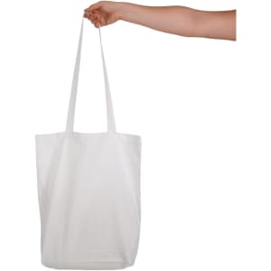A white cotton long handle bag being held by a hand, featuring two sturdy handles and no visible logos.