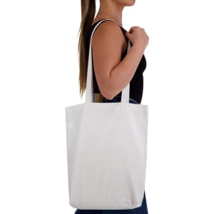 A white cotton long handle bag is being held by a person, showcasing its simple and versatile design.