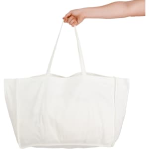 A hand holds a large, white reusable grocery bag with two sturdy straps. The bag has a plain design and no visible branding.