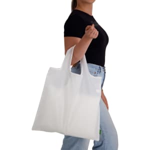 A white reusable grocery bag, held by a person, featuring handles and a simple design with a logo.