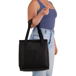 A black cooler bag with sturdy handles, held by a person wearing a blue top and light jeans.