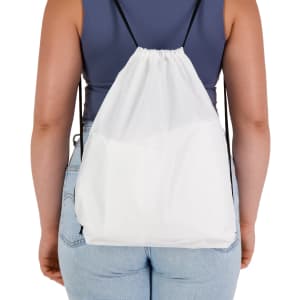 A white drawstring backpack with black straps, shown from the back on a person wearing a fitted top and jeans.